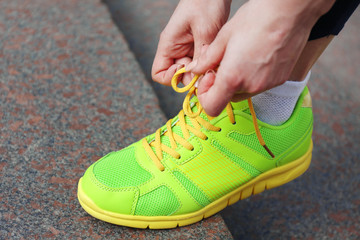 Young woman tying shoelace outside