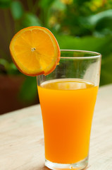 Glass of freshly pressed orange juice with sliced orange half on