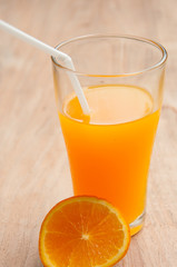 Glass of freshly pressed orange juice with sliced orange half on
