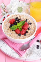 Tasty oatmeal with berries on table close-up
