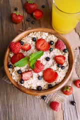 Tasty oatmeal with berries on table close-up
