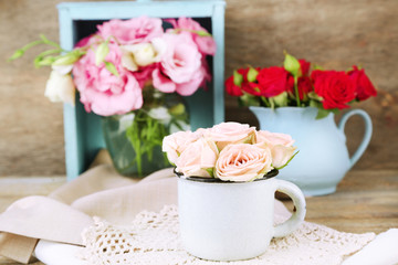 Beautiful flowers in vases on wooden background