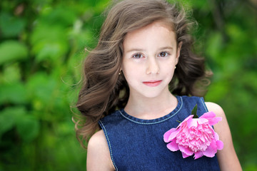 Fototapeta premium portrait of a beautiful little girl with peony