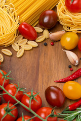 pasta, spices and cherry tomatoes on a wooden board