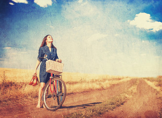 Brunette girl  with bycicle on countryside road.