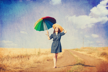 Brunette girl  with umbrella on country side road.
