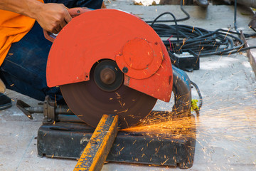 Worker cutting metal with grinder. Sparks while grinding iron