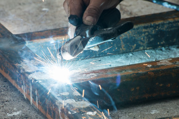 Worker welding steel with sparks lighting