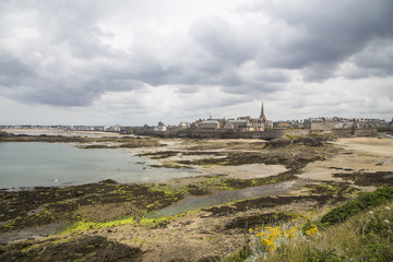 view of the shore from saint malo on a cloudy day - obrazy, fototapety, plakaty
