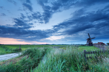 windmill on meadow at sunrise