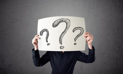 Businessman holding a paper with question marks in front of his