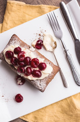 chocolate cake with cream cheese, raw cherry on white plate