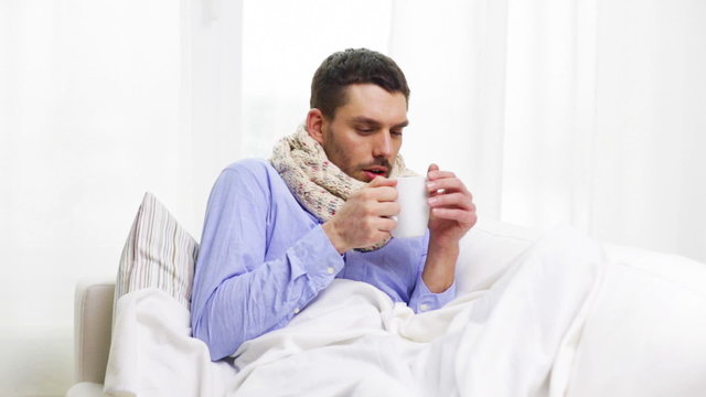 ill man with flu drinking hot tea at home