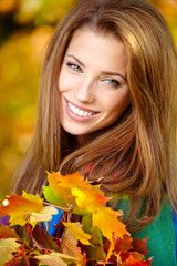 Beautiful elegant woman standing in a park in autumn