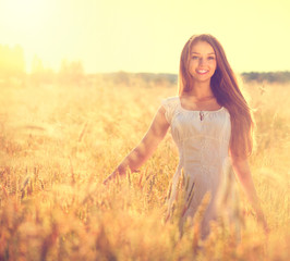 Beautiful teenage model girl in white dress running on the field