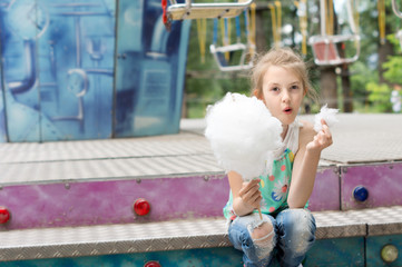 Laughing little girl eating candy floss at a fair