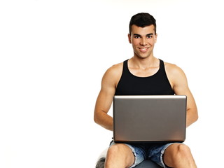 Young man sitting on the sport ball with computer