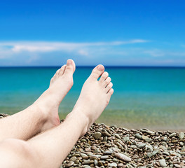 man's legs on the sand beach on a background of a sea landscape