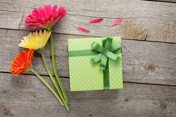 Three colorful gerbera flowers with gift box