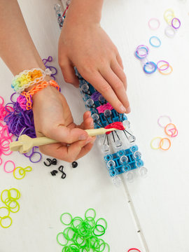 childs hands with band loom, croche hook and multicoloured elast