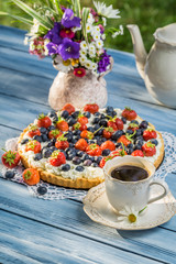 Fruit tart served with coffee in the summer garden