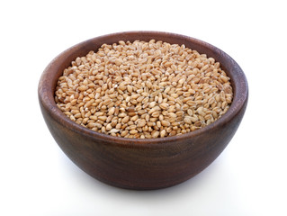 Ripe wheat in a wooden bowl on the old rustic table
