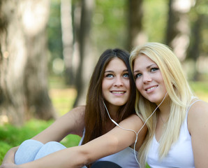 Happy teenage girls listening to music outdoors