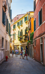 Fototapeta na wymiar Narrow canal among old colorful brick houses in Venice