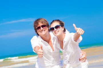 Front view of happy young couple on beach smiling and hugging.