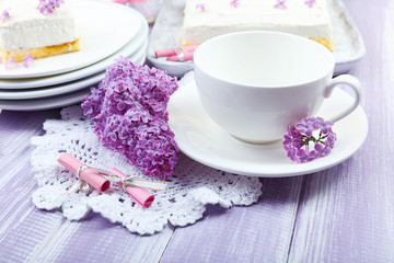Obraz na płótnie Canvas White cup with delicious dessert and lilac flowers