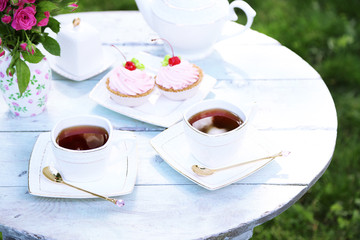 Coffee table with teacups and tasty cakes in garden