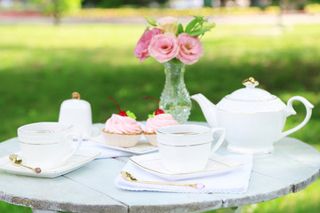 Coffee table with teacups and tasty cakes in garden