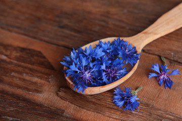Obraz na płótnie Canvas Cornflowers in wooden spoon on table close-up