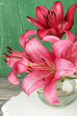 Beautiful lily in vase on wooden background