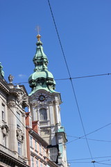 Fototapeta na wymiar Kirchturm mit Uhr der Stadtpfarrkirche in der Herrengasse Graz