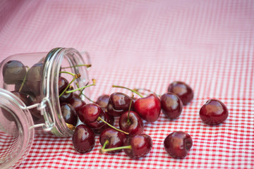 Glass storage jar full of fresh cherries