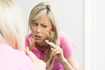 Unhappy woman looking to her damaged hair