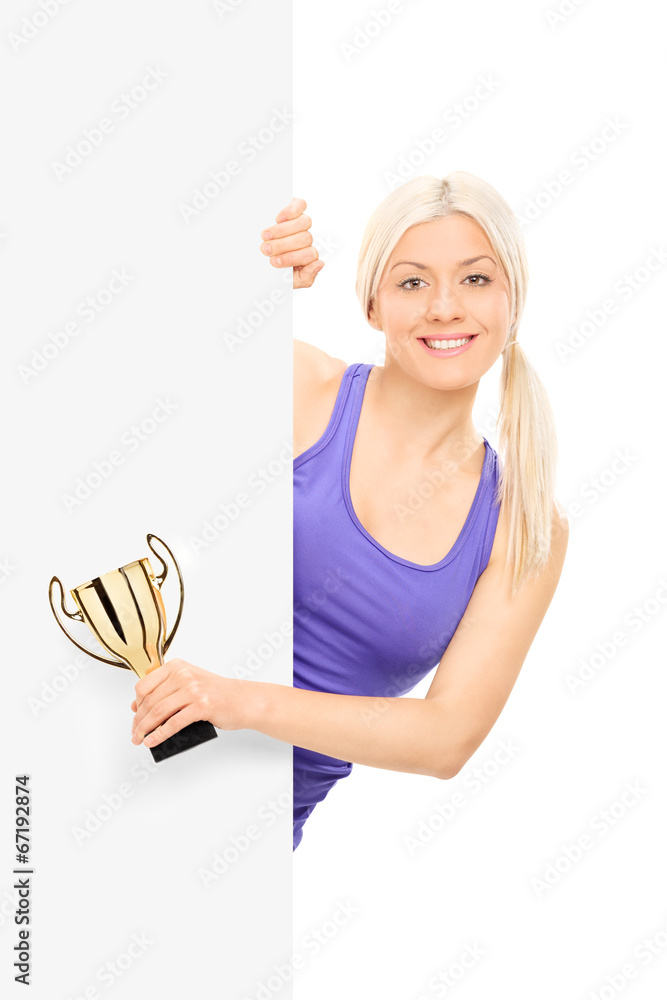 Wall mural female athlete holding a trophy behind a panel