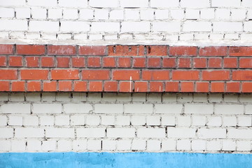 white brick wall with brown bricks and blue stripe