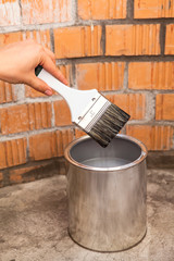 CLear paint brush in human hand over can with grey color