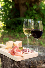Red and white wine in a glass with sausage and ham