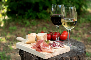 Red and white wine in a glass with sausage, ham and tomatoes