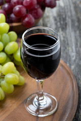 glass of red wine and grapes on a wooden board
