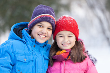 sister and brother smiling and hugging outside.