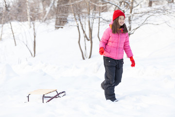 Fototapeta na wymiar young girl walking on snow with sledges.