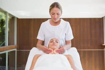 Peaceful brunette getting facial from beauty therapist