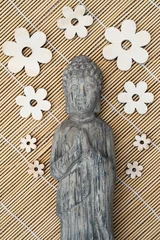 Foto auf Acrylglas Stenen  grijze Boeddha met houten bloemen © trinetuzun