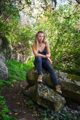 Naklejka na ściany i meble Young girl sitting on a rock