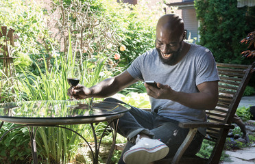 Naklejka na ściany i meble Man Laughs Reading Text Message in Garden