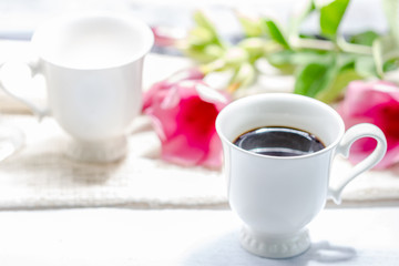 cup of coffee and pink flower on white wooden table